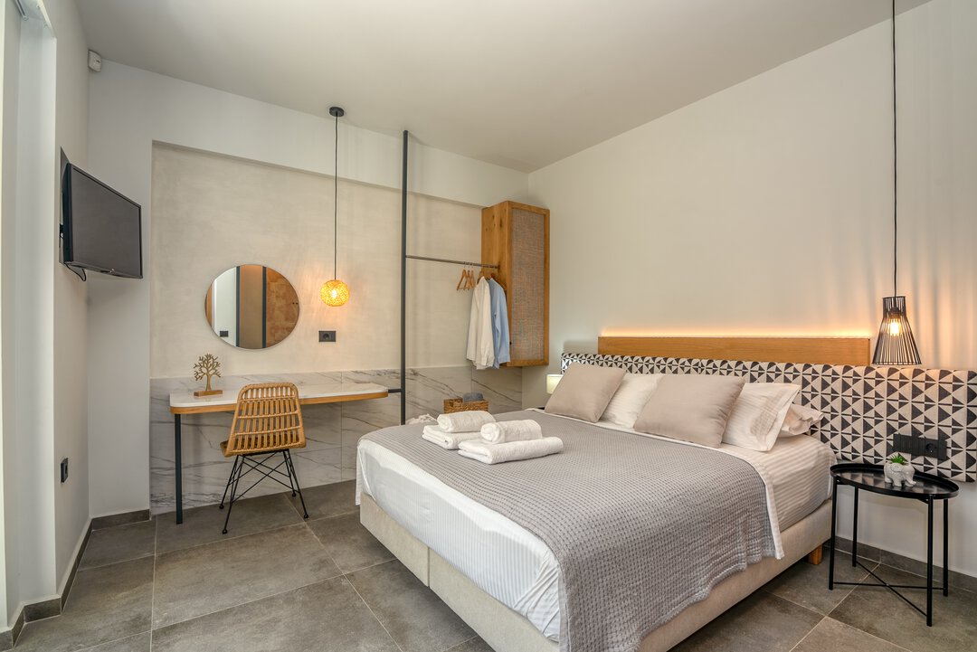 Modern master bedroom with geometric patterned headboard, oak wood furnishings, rattan accent chair, and ambient LED lighting at Nusa Gramvousa, Crete