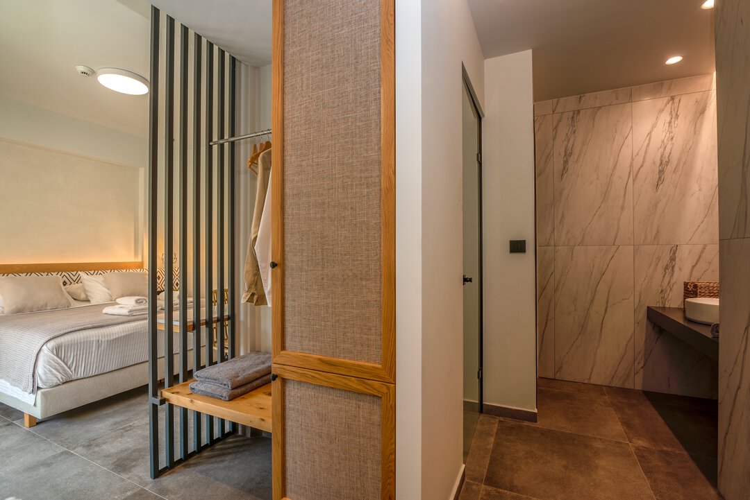 Open-plan suite showing bedroom and marble bathroom connection at Nusa Balos, Crete