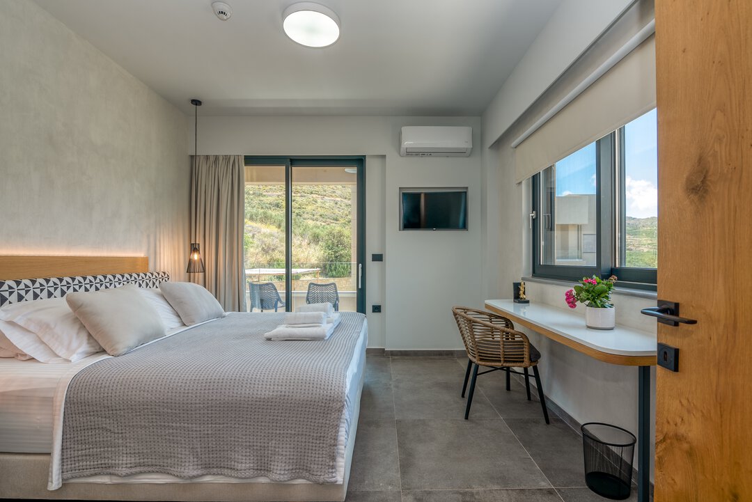 Open-plan kitchen and dining with rattan pendants and garden views at Nusa Balos villa, Crete